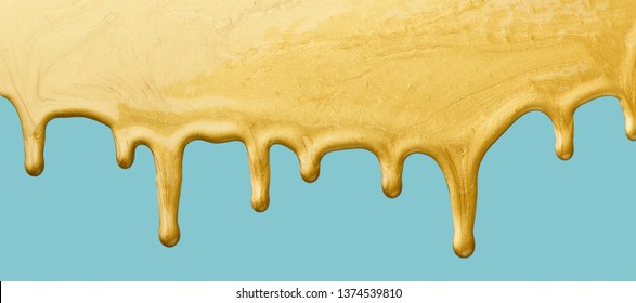 Golden paint dripping on blue background, copy space