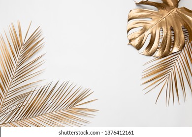 Golden painted tropical date palm and monstera leaves on plain white background isolated. Creative botanical layout border frame. Chic wedding invitation card mockup. Empty space, room for text. 