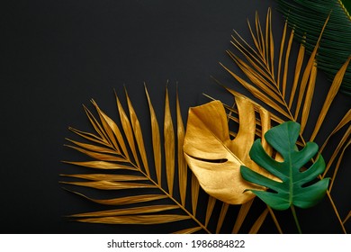 Golden palm leaf and green fresh tropical monstera leave texture frame on dark black background with copy space. Painted gold leaves forest pattern on summer nature floral background - Powered by Shutterstock