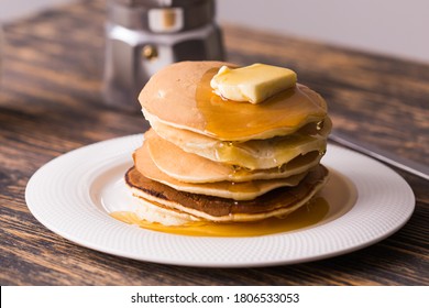 Golden pancakes with butter and warm maple syrup.