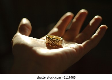 Golden Peace Keeper Ring Made Of Pieces In Dramatic Light In A Palm