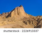 Golden Peak - A closeup view of evening sunlight shining on towering Manly Beacon at Badlands, Death Valley National Park, California, USA.