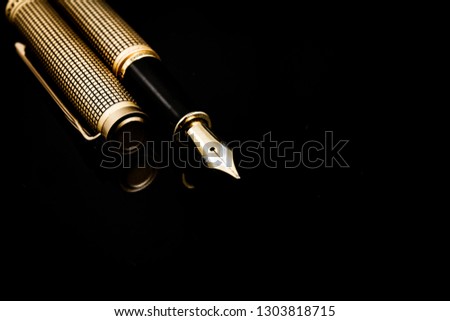 Golden pen on a dark isolated background