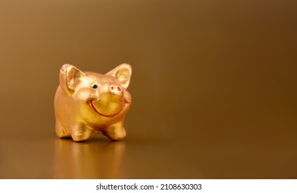 Golden piggy toy on a gold background frame stock images. Cute little pig figurine on a gold background with copy space for text stock images