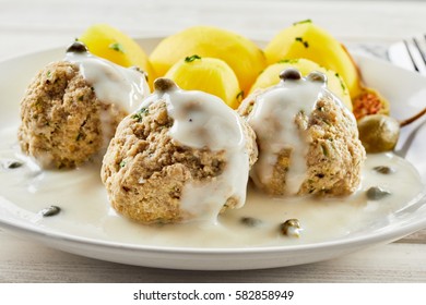 Golden Potatoes With Herbs In Dish With Meatballs Served With A White Sauce And Capers. In German It Called Königsberger Klopse.