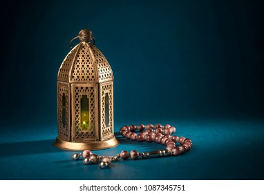 A golden Ramadhan lamp with Islamic rosary beads on dark background. Ramadan - an important Islamic festival. Islamic festive greeting card photo.