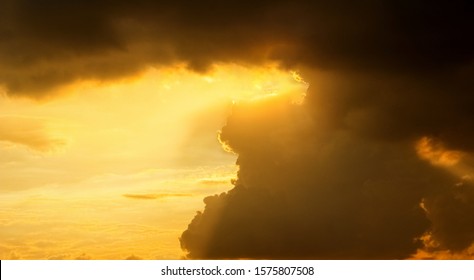 Golden rays in the clouds and sky, when the sun sets.Golden Sun Rays Break Through the Clouds - Beautiful Nature Background. Dramatic sunset like fire in the sky with golden clouds.