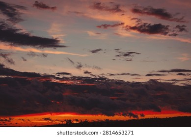 Golden rays of the setting sun blend with soft clouds, creating a breathtaking display of colors in the evening sky above a peaceful landscape.