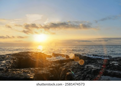 Golden rays spill across the horizon, illuminating the rocky coastline as gentle waves lap against the shore, embodying serenity and the beauty of nature at dusk. - Powered by Shutterstock - Get 15% off with code: PIKWIZARD15