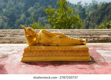Golden reclining Buddha statue at Tiger Cave Temple in Thailand, showing detailed Buddhist sculpture and traditional Thai design. The temple is known for its hilltop viewpoint, large stairway, and important religious landmarks in the Krabi region.