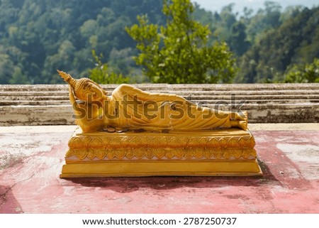 Golden reclining Buddha statue at Tiger Cave Temple in Thailand, showing detailed Buddhist sculpture and traditional Thai design. The temple is known for its hilltop viewpoint, large stairway, and important religious landmarks in the Krabi region.