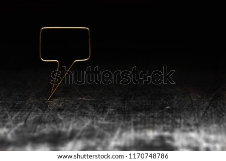 Golden remark. Blank speech bubble made of gold wire on rustic or grunge wood ready for inserting text. Dark background. Shallow depth of field.