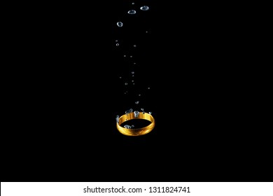 Golden ring dropped into the water in the bubbles on a black background - Powered by Shutterstock