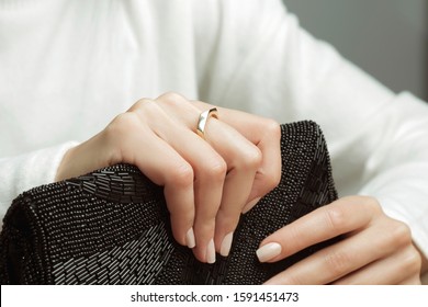 Golden ring in hand of young lady holding black purse in hand