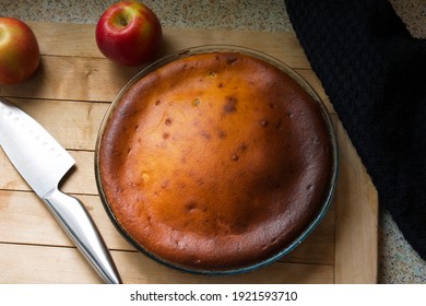 Golden Round Freshly Baked Quark Apple Cake In A Mould On A Wooden Board Next To A Knife