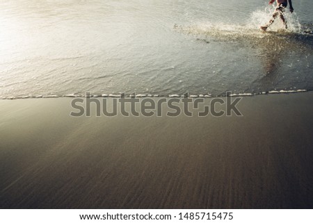 Golden sand beach shore texture with person splashing water with feet