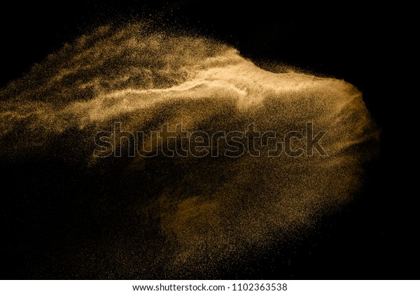 Golden sand explosion isolated on black\
background. Abstract sand cloud. Golden colored sand splash against\
dark background. Yellow sand fly wave in the\
air.