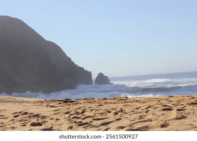 Golden sandy beach at Gray Whale Cove State Beach, with dramatic rocky cliffs and crashing ocean waves creating a stunning coastal view - Powered by Shutterstock