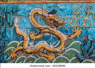 Golden scaled imperial dragon with white crest floating in green stormy waves on the nine dragon wall in the Forbidden City in Beijing - Shutterstock ID 403188985
