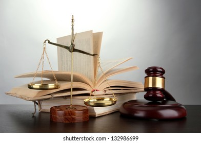 Golden scales of justice, gavel and books on grey background