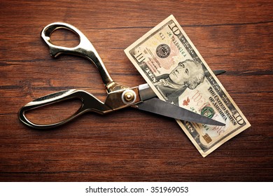 Golden Scissors Cut Money On Wooden Background