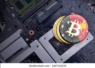 Golden Shining Bitcoins With Flag Of Papua New Guinea On A Computer Electronic Circuit Board. Bitcoin Mining Concept.