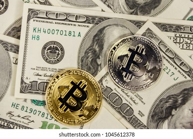 Golden and silver bitcoins on hundred dollar bills background