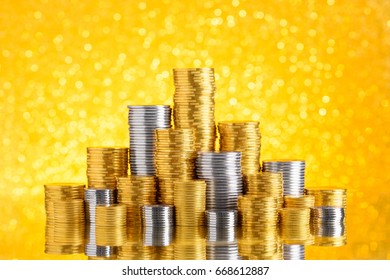 Golden And Silver Coins Stacked On Gold Glitter Bokeh Background