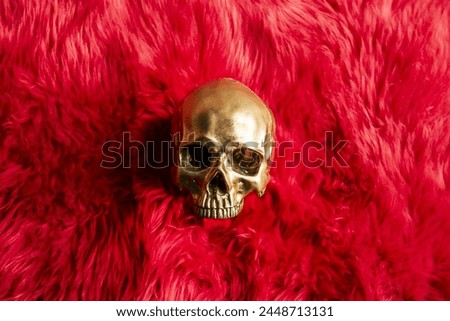 golden skull lying on a fluffy red fur cushion posing for the camera looking bored