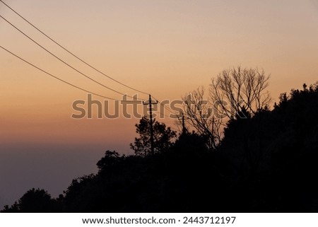 The golden sky at dusk and the silhouette of black trees on the mountains