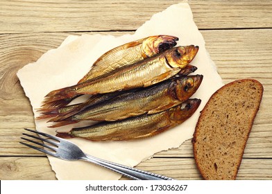 Golden smoked fish on board with a fork and bread