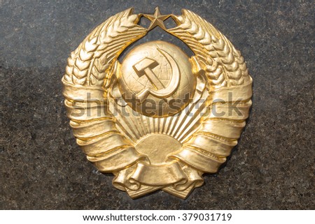 Golden soviet CCCP emblem with hammer and sickle on a marble plate