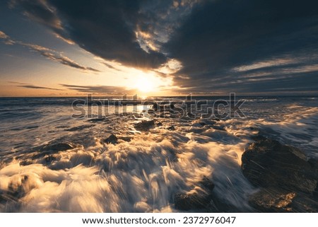 Golden splashing waves, rocky beach shore and sunrise sea horizon