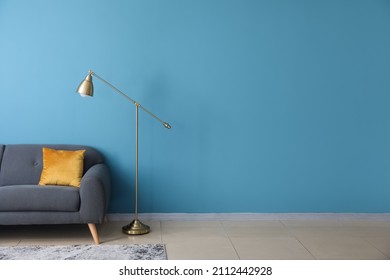 Golden Standard Lamp And Sofa Near Blue Wall