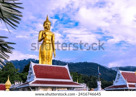 Golden Standing Buddha statue on the hill and blue sky at Hatyai, Songkhla, Thailand.