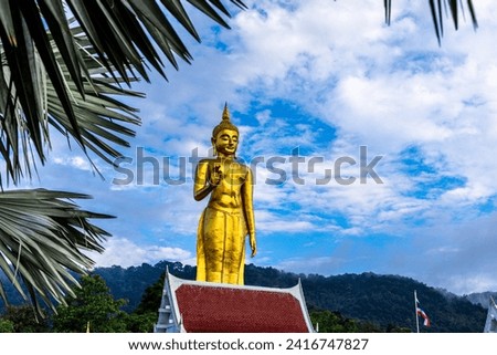 Golden Standing Buddha statue on the hill and blue sky at Hatyai, Songkhla, Thailand.