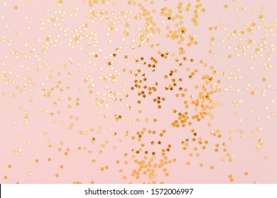 Golden Star Glitter Confetti On Pale Pink Background. Festive Holiday Background. Celebration Concept. Top View, Flat Lay.