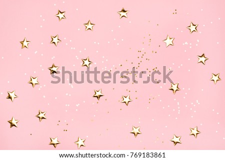 Golden stars glitter on pink background. Festive holiday pastel backdrop.