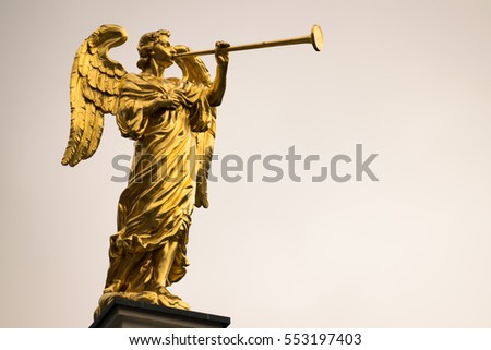 Golden statue of an angel with a trumpet and copy space.