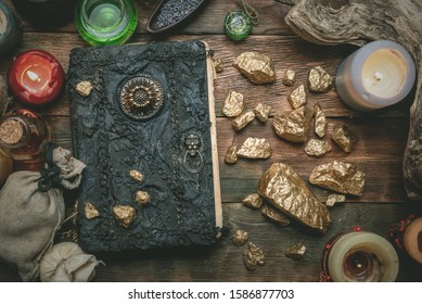 Golden stones and ancient magic book on alchemist table concept background. - Shutterstock ID 1586877703