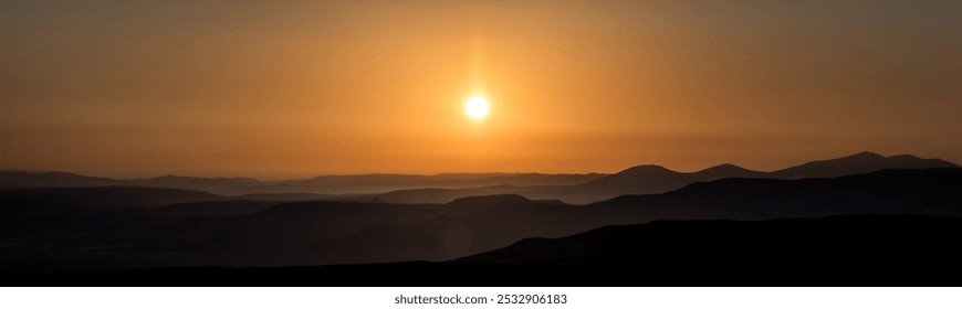 Golden sun sets over layered, misty hills, casting a warm glow across the tranquil landscape, blending sky and earth in peaceful harmony. - Powered by Shutterstock