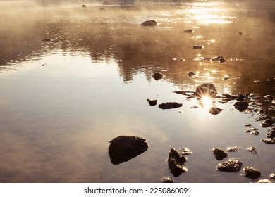 Golden sunbeams and ripple glare on calm river water surface with fluffy yellow fog, reflection in early morning. Bright, warm and quiet sunrise background, detail, texture. - Powered by Shutterstock