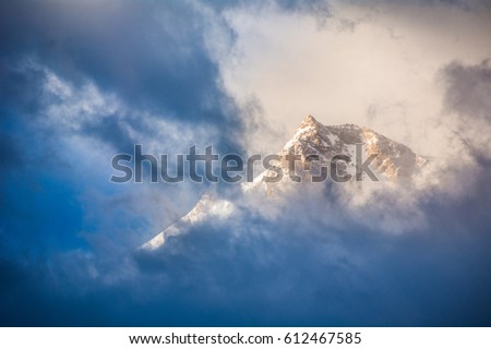 Golden sunrise behind dark blue clouds passing over the peak of Nanga Parbat mountain in the Himalayas in northern Pakistan