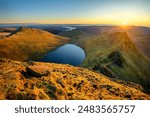 Golden sunrise from Helvellyn in The Lake District, overlooking Striding Edge and Ullswater.