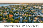  Golden sunrise light bathes downtown Charleston, South Carolina, with historic buildings and streets visible from an aerial view.