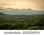 Golden sunrise over the lush forest of Santa Rosa National Park with the Guanacaste volcanic range in the backdrop. Costa Rica