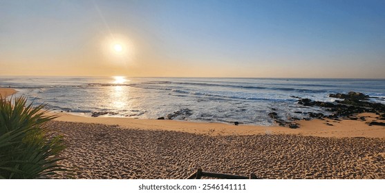 Golden sunrise over serene beach with gentle waves. - Powered by Shutterstock