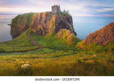 Golden sunrise or sunset light on the coastal landscape ruins of Donnottar Castle on the Aberdeenshire coast of Scotland. - Powered by Shutterstock