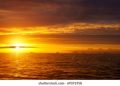 Golden Sunset In Antarctic Sea. Shadows Of Icebergs On The Horizon.