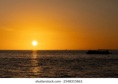 Golden sunset over the ocean with a silhouetted boat and a flying bird, reflecting warm light across the calm water. - Powered by Shutterstock